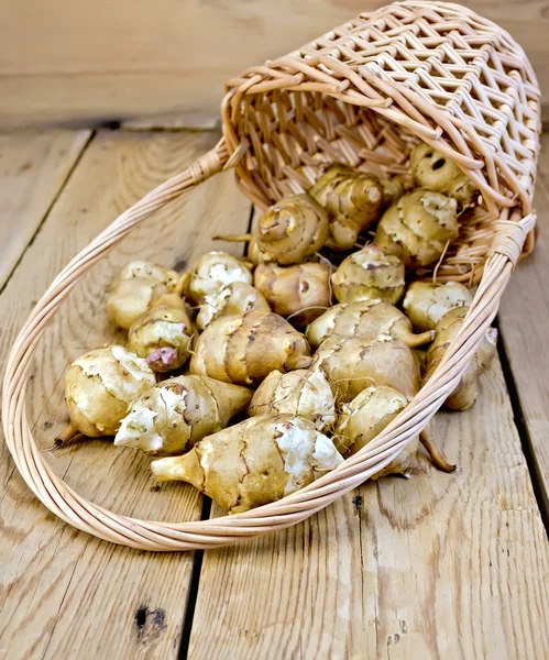 Jerusalem artichokes with basket on board — Stock Photo, Image