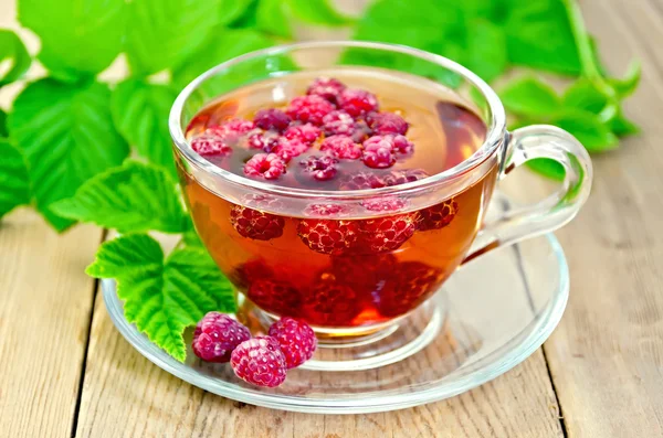 Tea with raspberry and green leaves on board — Stock Photo, Image