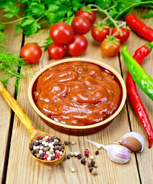 Ketchup in pottery with spices on board — Stock Photo, Image