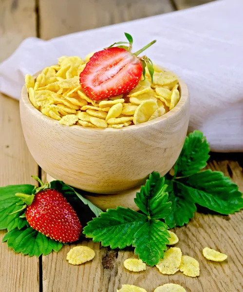 Cornflakes in wooden bowl with strawberries on board — Stock Photo, Image