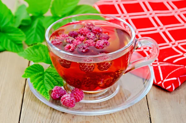 Tea with raspberry and a napkin on board — Stock Photo, Image