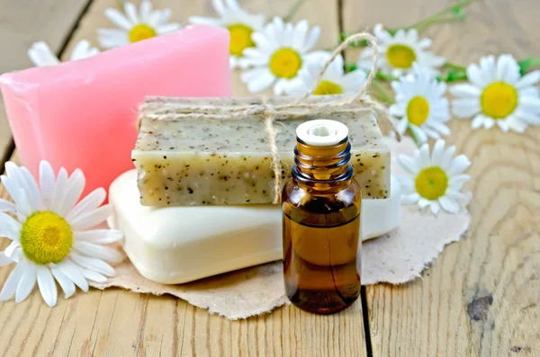 Oil with different soap and camomile on board — Stock Photo, Image