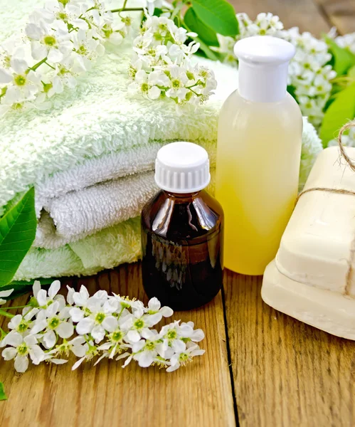 Oil with lotion and bird cherry on board — Stock Photo, Image