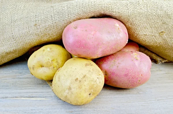Картопля жовта і червона з мішковиною на дошці — стокове фото