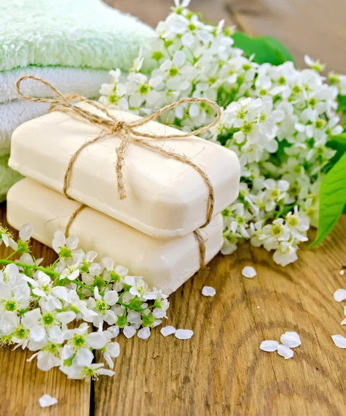 Soap with towel and bird cherry on board — Stock Photo, Image