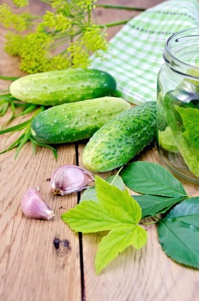 Komkommers met kruik en knoflook aan boord — Stockfoto