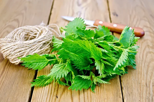 Nettle with a knife and twine on board — Stock Photo, Image