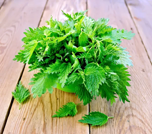 Nettles in a green bowl on board — Stock Photo, Image