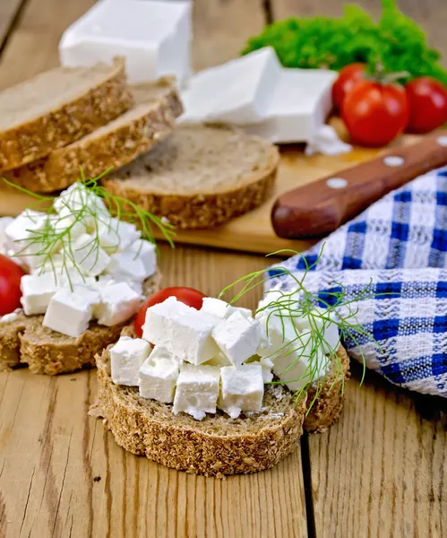Bread with feta and tomatoes on board with knife — Stock Photo, Image