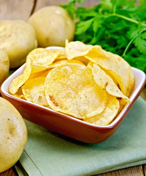 Chips in bowl with potato on napkin and board — Stock Photo, Image