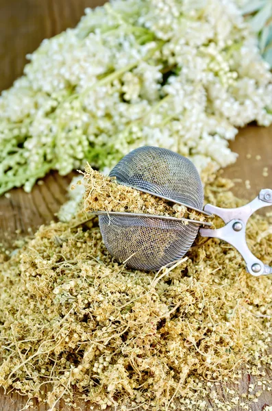 Herbal tea from dry meadowsweet in strainer on board — Stock Photo, Image