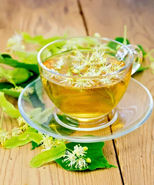 Трав'яний чай з квітів липи в скляній чашці на дошці — стокове фото