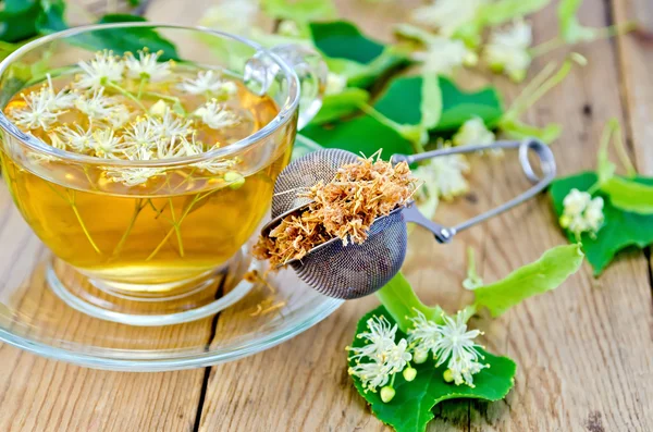 Herbal tea from linden flowers with strainer on board — Stock Photo, Image