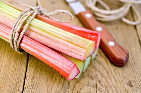 Rhubarb with twine and knife on board — Stock Photo, Image