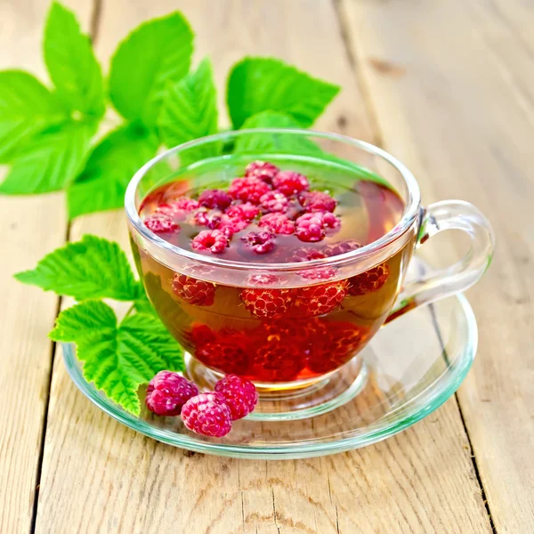 Té con frambuesas en taza de vidrio a bordo —  Fotos de Stock