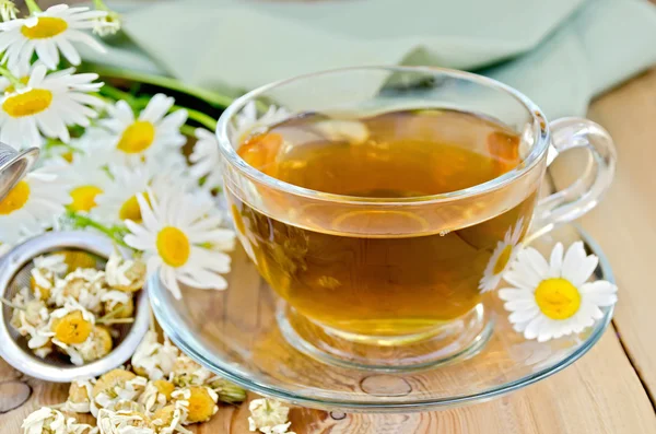 Té de manzanilla de hierbas en taza con colador a bordo —  Fotos de Stock