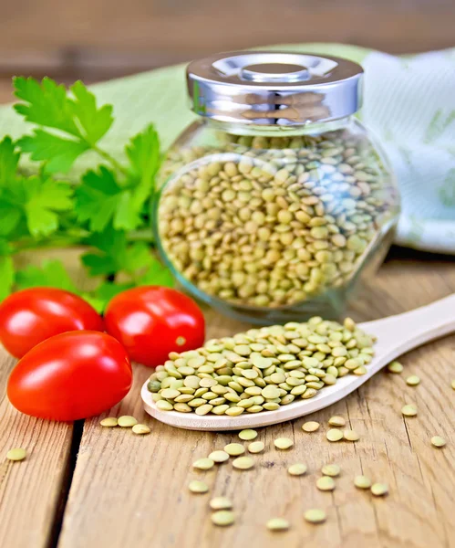 Lentils green in jar and spoon with tomatoes on board — Stock Photo, Image