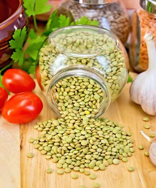 Lentils green in jar with tomato on board — Stock Photo, Image