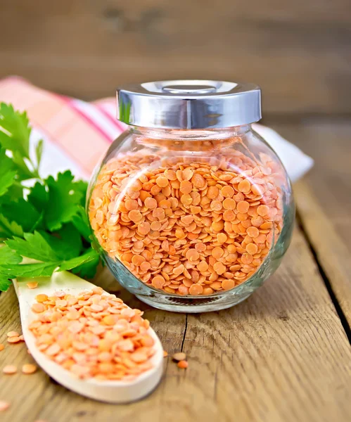 Lentils red in jar and spoon on board with parsley — Stock Photo, Image