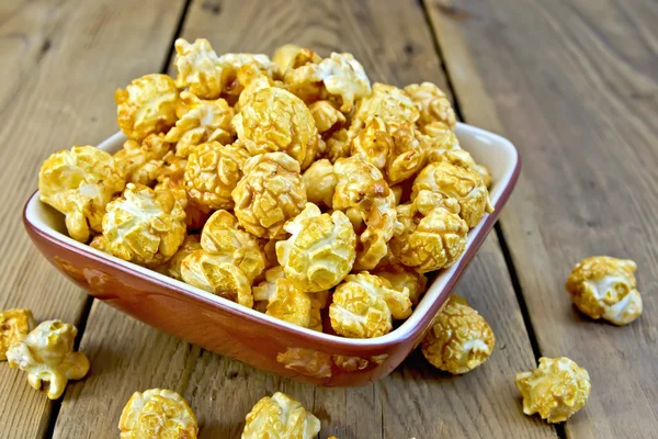 Popcorn caramel on board in clay bowl — Stock Photo, Image