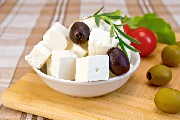 Feta avec olives en tasse sur tissu brun et planche — Photo
