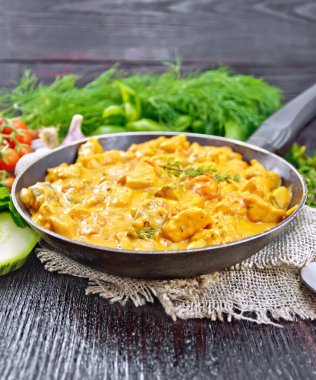 Hindi eti kebabı domates, kabak, ekşi krema ve kekik tavada çuval bezi, kaşık ve sarımsak siyah tahta arka planda.