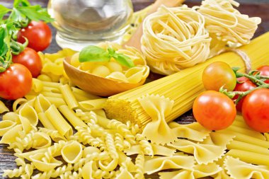 Kaşık içinde makarna kabukları, pipo rigonu, spagetti, tagliatelle, fusilli, penne, farfalle, trenette, rotini, domates, sarımsak, sebze yağı sürahide ve lahanada maydanoz.