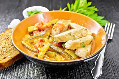 Kızarmış tavuk göğsü dilimleri haşlanmış kabak, domates ve sarımsak tabakta, ekmek, maydanoz ve tahta arka planda bir çatal.