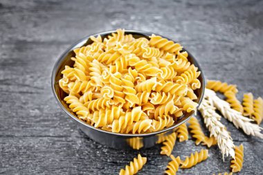 Tam tahıllı buğday unlu fusilli makarna, tahtadan arka planda buğday dikenleri.