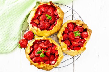 Metal ızgarada çilekli küçük turta, ahşap tahtanın arka planında peçete.