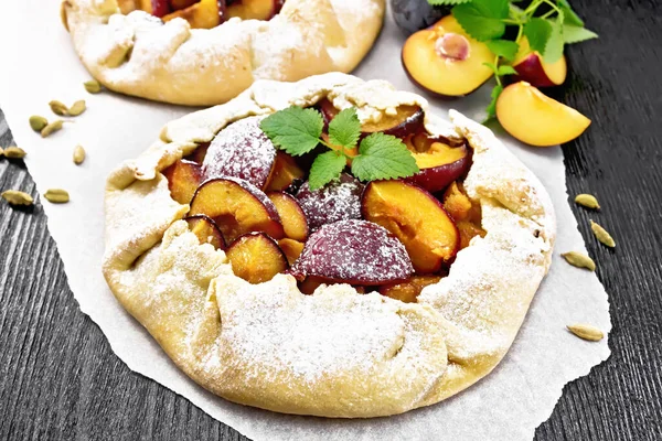 Erikli iki tatlı turta, kağıt üzerinde şeker ve kakule, tahta zeminde yeşil nane filizi