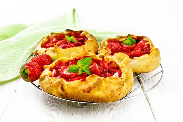 Metal ızgarada çilekli küçük turta, tahta bir arka planda havlu.