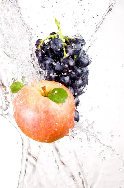 Juicy red apple and bunch of grapes in water splash isolated on — Stock Photo, Image
