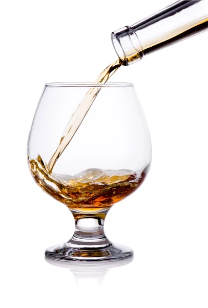 Pouring from bottle of cognac in glass isolated on white backgro — Stock Photo, Image