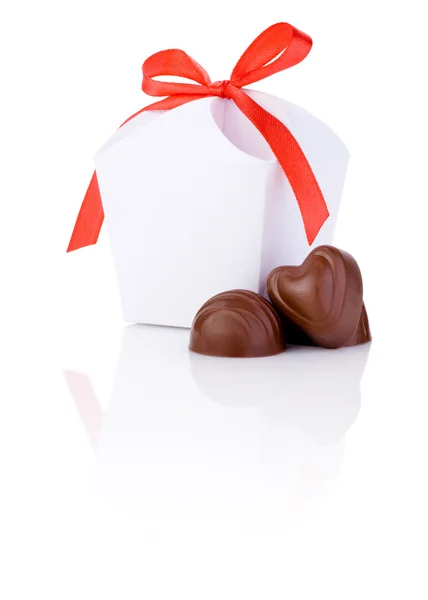 Doces de chocolate e presente branco na forma de coração com um arco — Fotografia de Stock