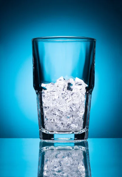 Vidro vazio com gelo isolado em um fundo azul — Fotografia de Stock