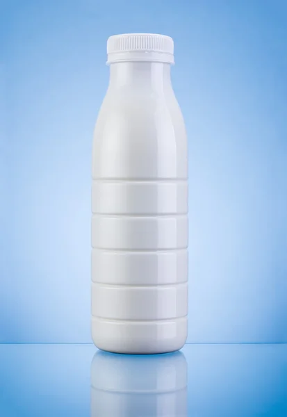 Białe plastikowe butelki mleka na niebieskim tle — Zdjęcie stockowe