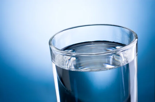 Primer plano vaso de agua sobre un fondo azul —  Fotos de Stock