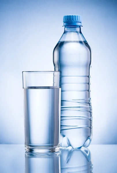 Plastic fles en glas drinkwater geïsoleerd op blauwe terug — Stockfoto