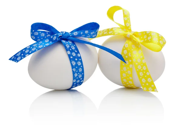 Dwa jaja wielkanocne z uroczysty kokarda niebieski i żółty na białym tle na whi — Zdjęcie stockowe