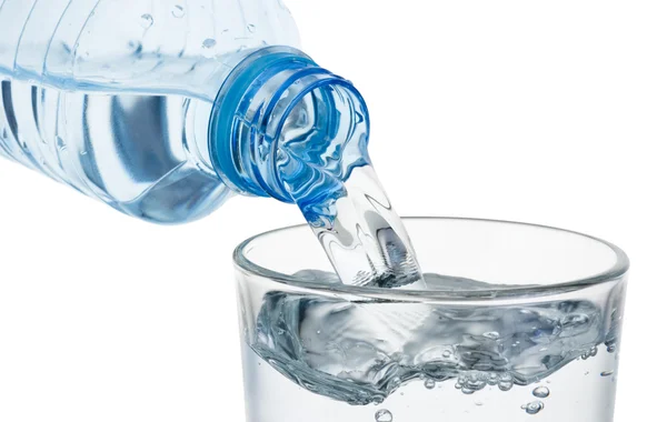 Verter vidro de água de uma garrafa de plástico isolado em b branco — Fotografia de Stock