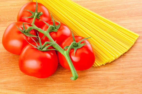 Bund Spaghetti Nudeln und reife Tomaten an Zweig Nahaufnahme auf — Stockfoto