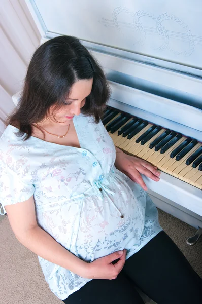 La femme enceinte près d'un piano — Photo