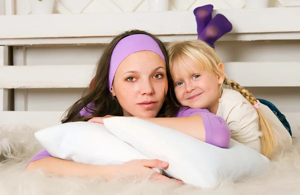 Жінка в фіолетовому одязі з дівчиною лежить на підлозі — стокове фото