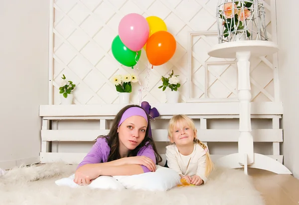 Žena ve fialové šaty s dívkou leží na podlaze — Stock fotografie