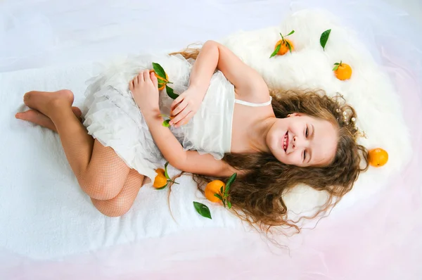 Mooi meisje liggen onder mandarijnen — Stockfoto
