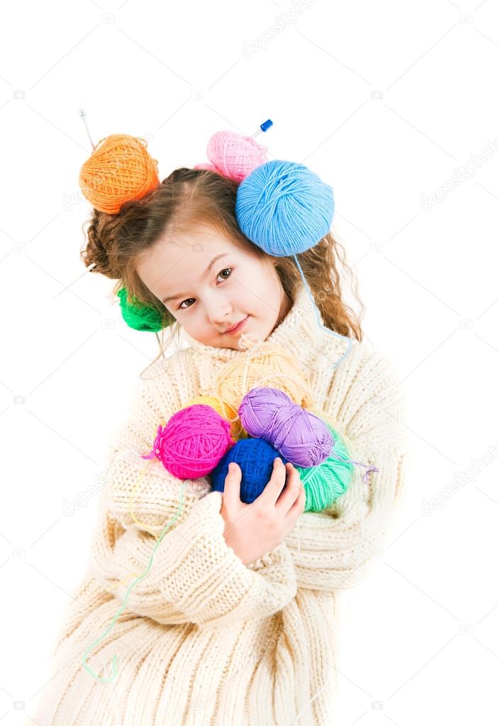 Girl with knitting spokes and balls of threads in hair