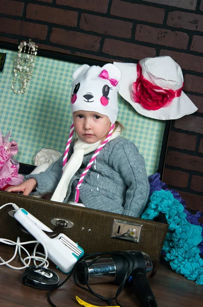 Little warmly dressed girl packs a suitcase with summer things — Stock Photo, Image