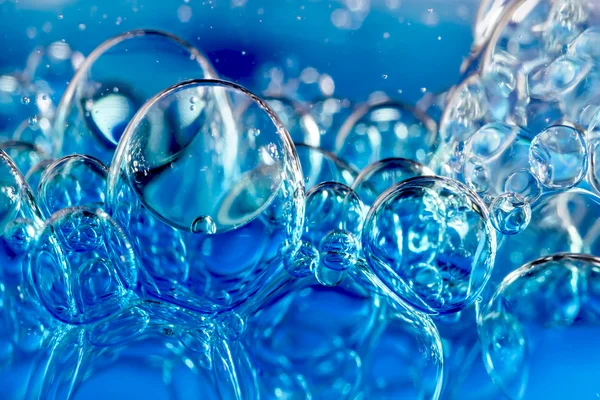 Bolhas azuis em água clara contra branco — Fotografia de Stock