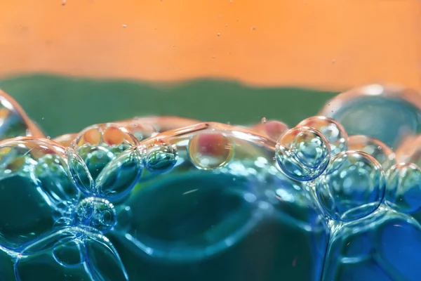 Blå bubblor i klart vatten mot orange — Stockfoto